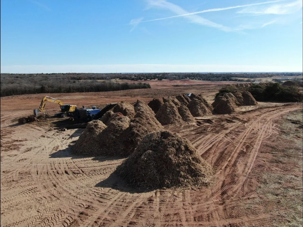 Aerial view of mulch piles rowed out across freshly cleared Oklahoma land in winter