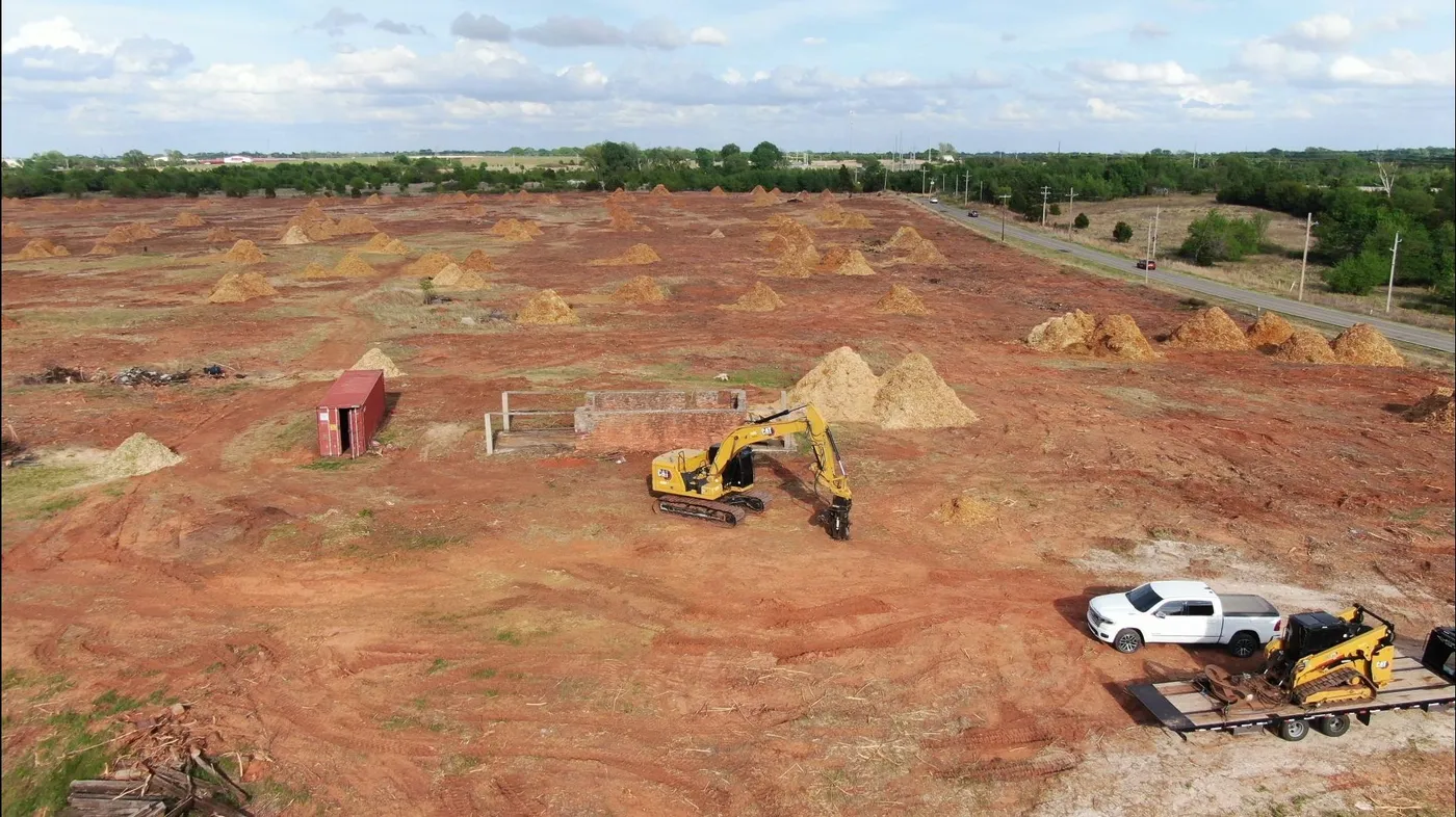 Aerial view of a large land clearing project dotted with mulch piles throughout the property