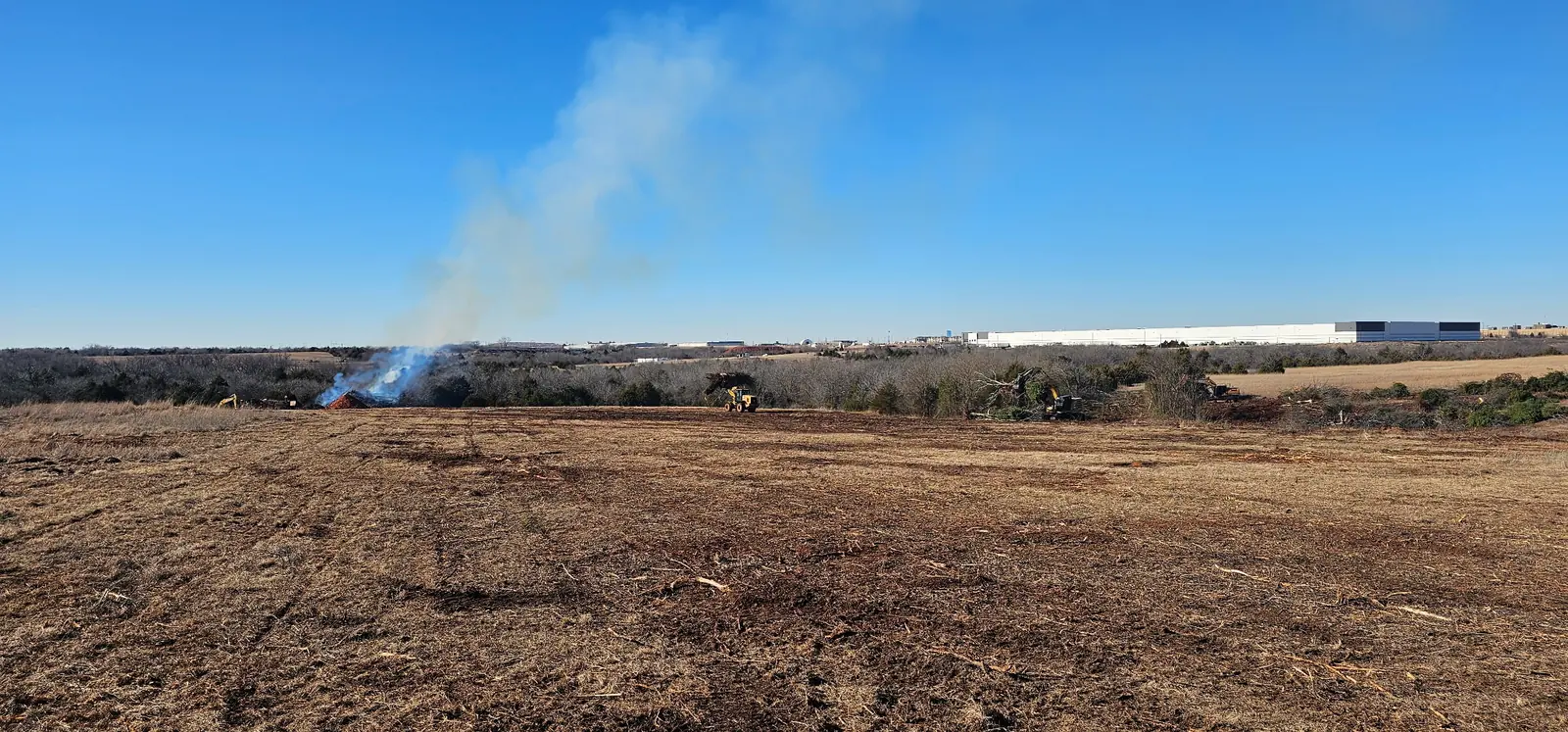 Smoke drifting across a freshly cleared field from a distant burn pile in Oklahoma