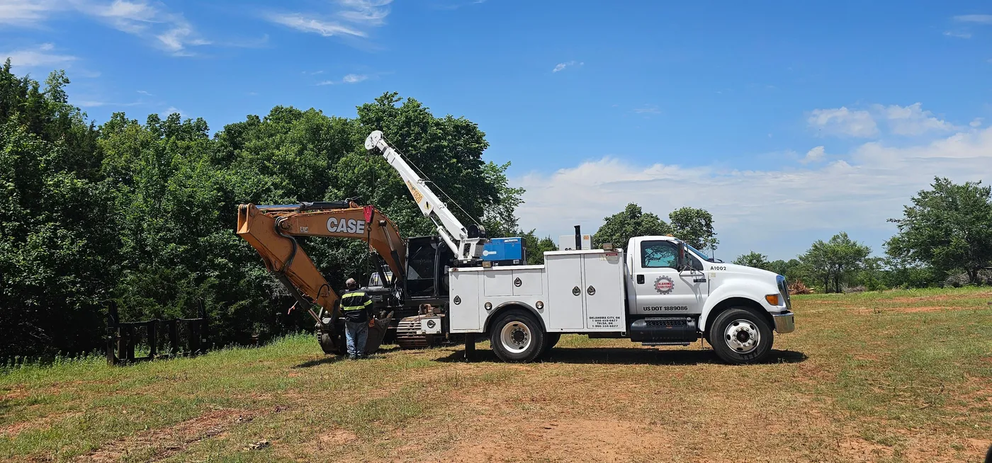 Mechanic truck with a crane servicing a tracked excavator on a land clearing job site in Oklahoma