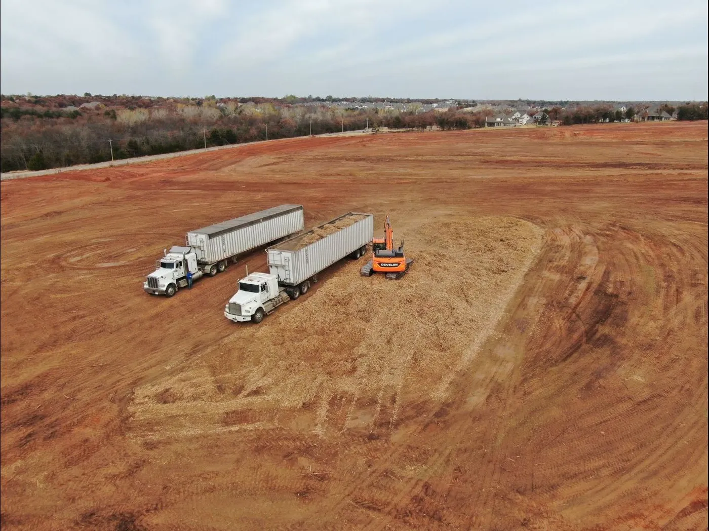 Two walking floor semi trailers being loaded with ground wood mulch for haul off on an Oklahoma clearing job